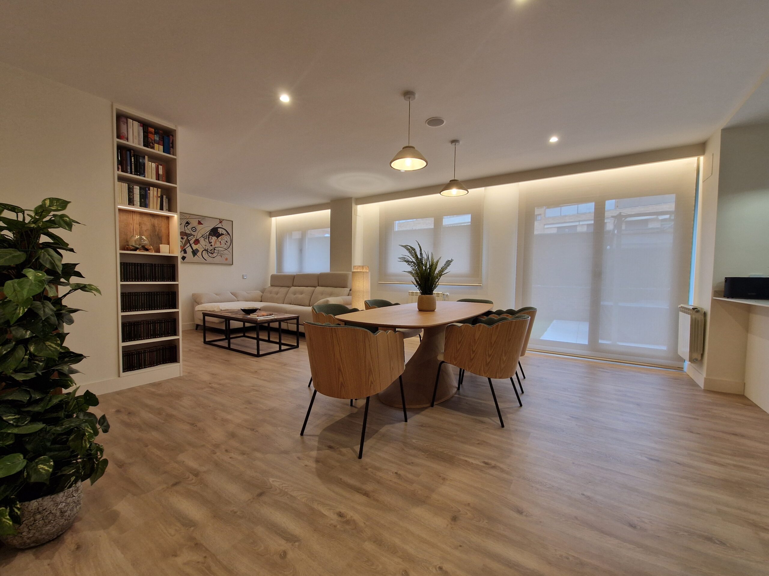 Comedor moderno y luminoso con estantería y plantas.