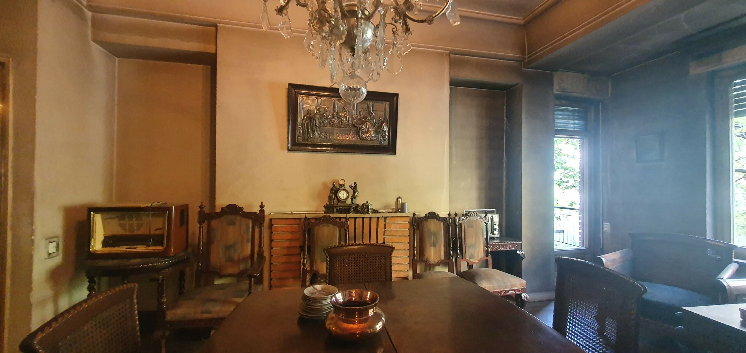 Comedor antiguo con muebles de madera y lámpara de araña.