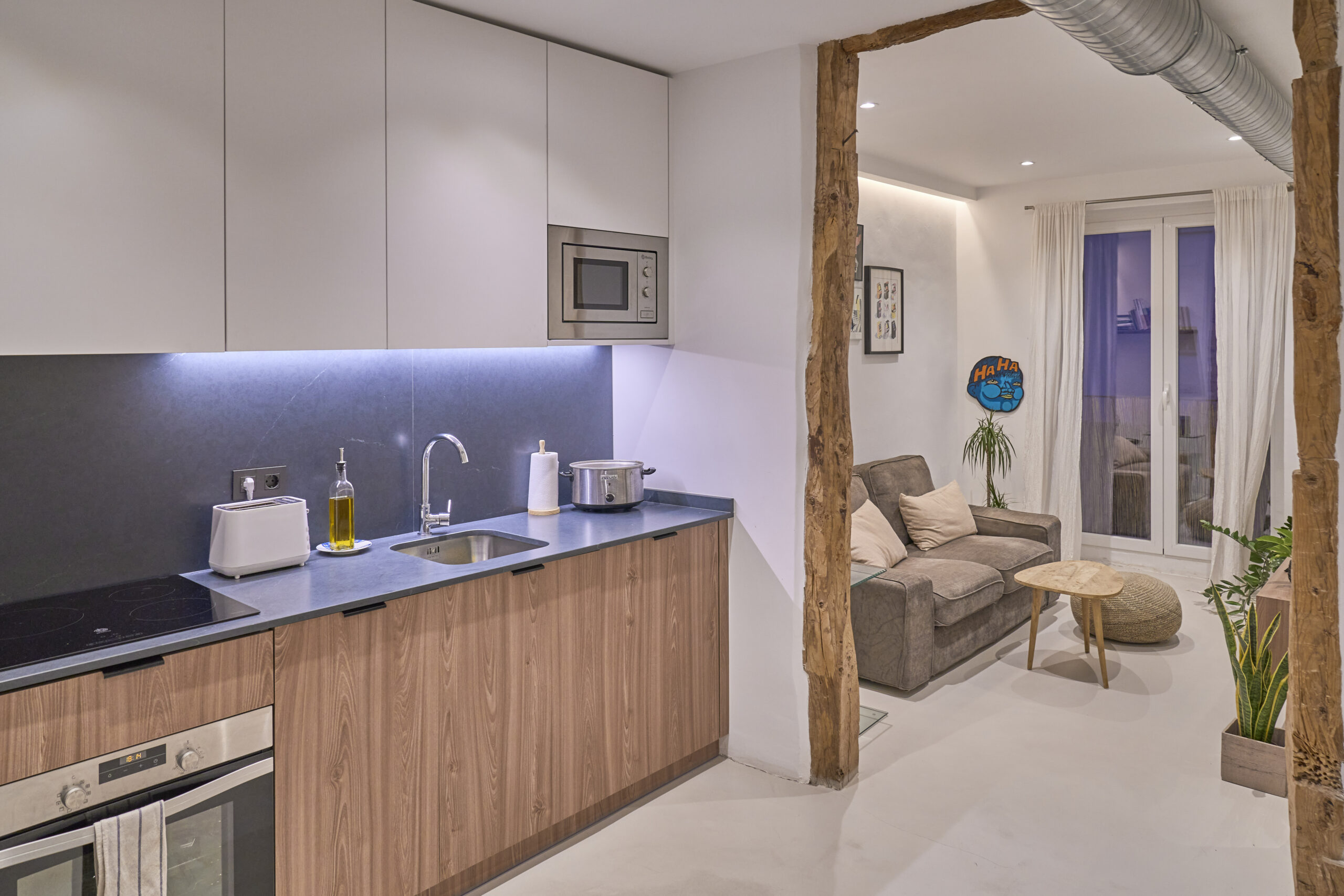 Cocina moderna integrada con salón y vigas de madera.