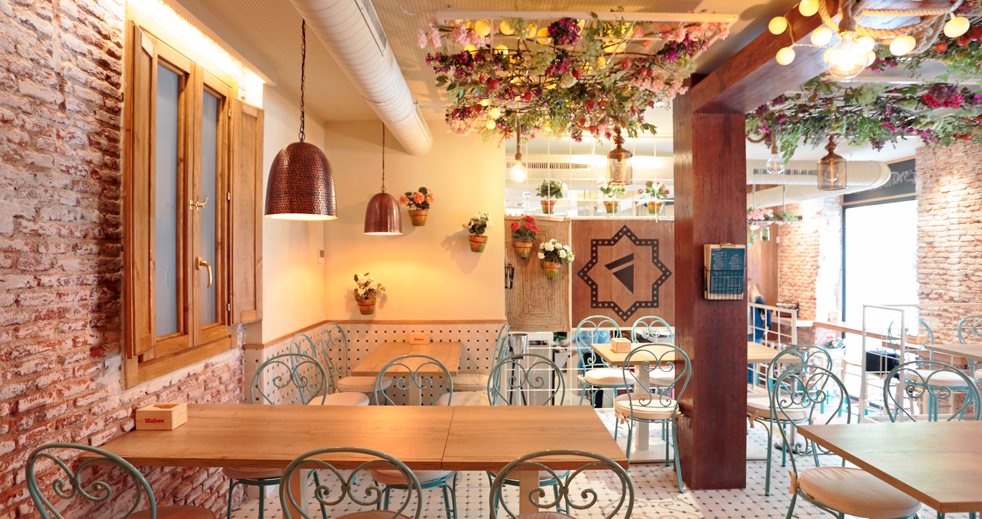 Interior de cafetería decorada con flores y ladrillo visto.