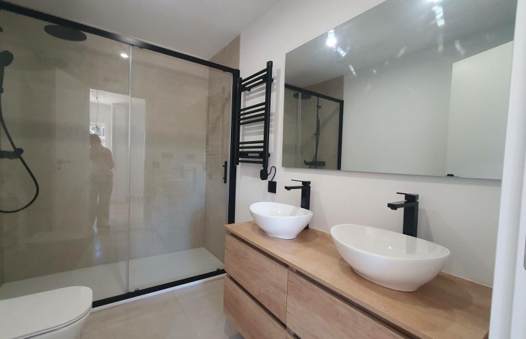 Baño moderno con ducha, lavabo y toallero negro.