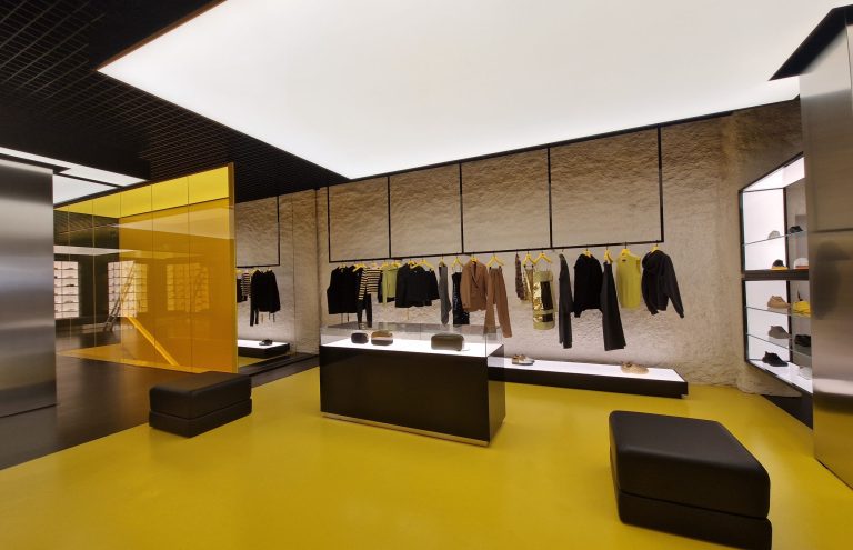 Interior moderno de tienda de ropa con suelo amarillo.