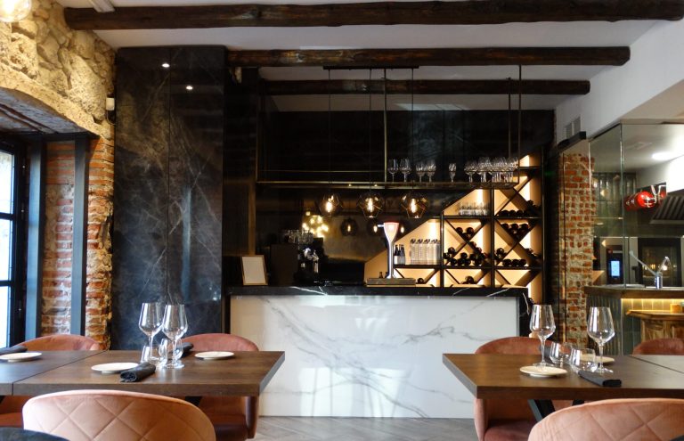 Interior moderno de restaurante con barra y mesas preparadas.