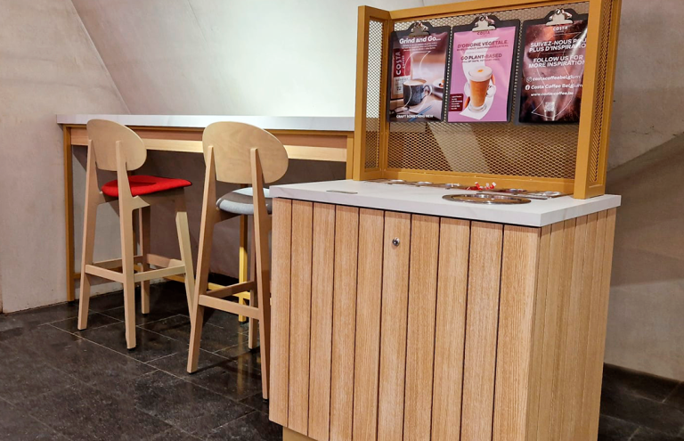 Barra de cafetería Costa Coffee con taburetes y cartelería.