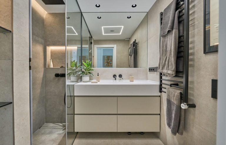 Baño moderno con ducha, lavabo y toallas colgadas.