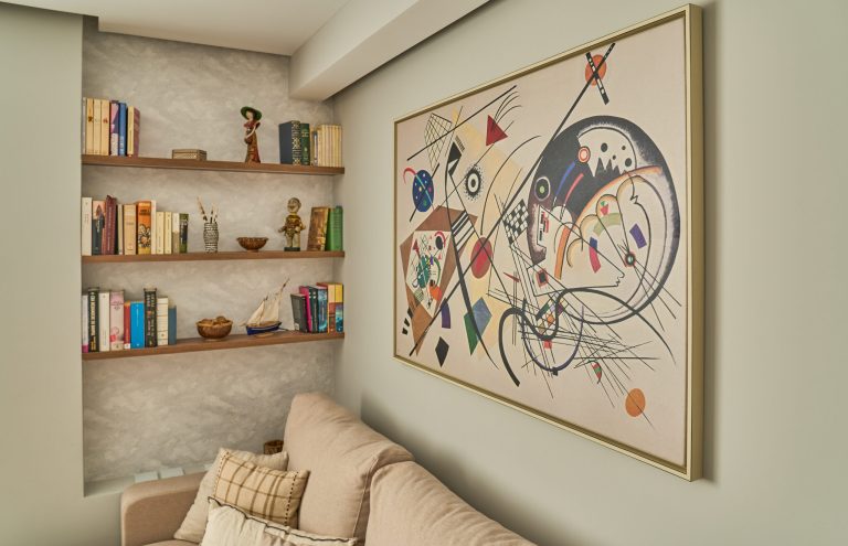Cuadro abstracto Kandinsky y estantería con libros y adornos.