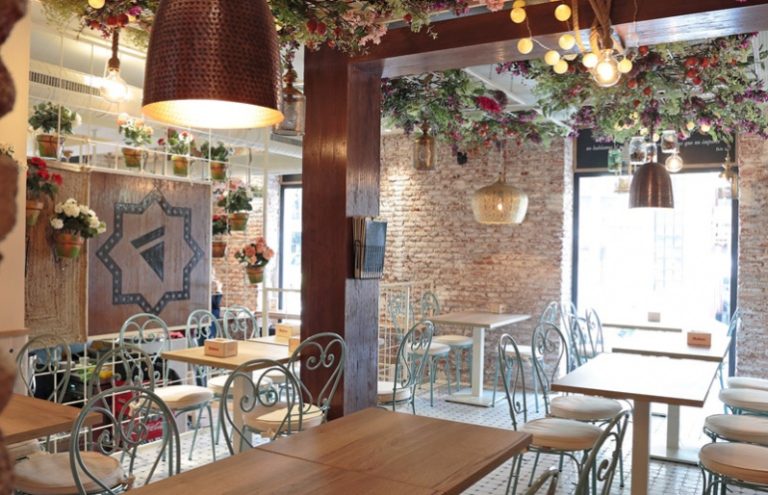 Interior de restaurante decorado con flores y ladrillo visto.