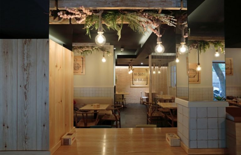 Interior de restaurante con decoración rústica y plantas colgantes.